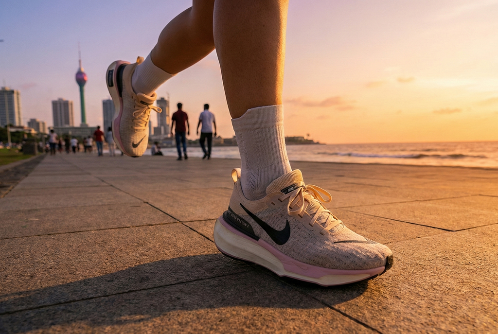 Women wearing Nike Invincible 3 Premium running shoes with a Nike logo on a city beach at sunset.