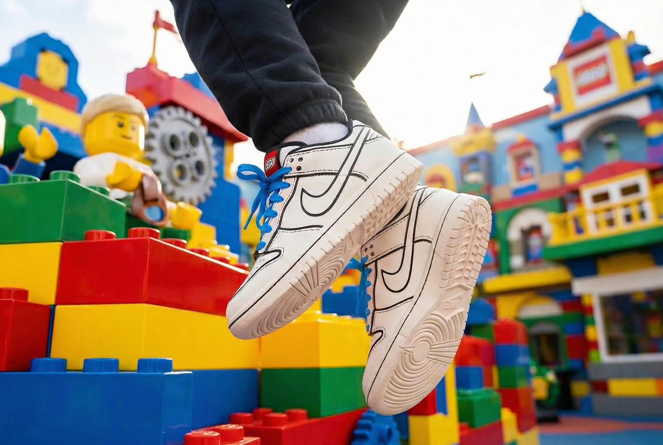 Colorful toy building set with a child's foot wearing Nike Dunk Low x LEGO® Collection stepping on it.