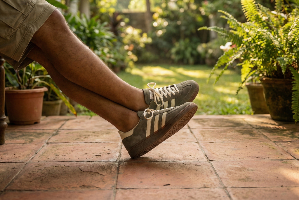 Person wearing Adidas Handball Spezial Shoes sitting on a patio with plants and garden in the background