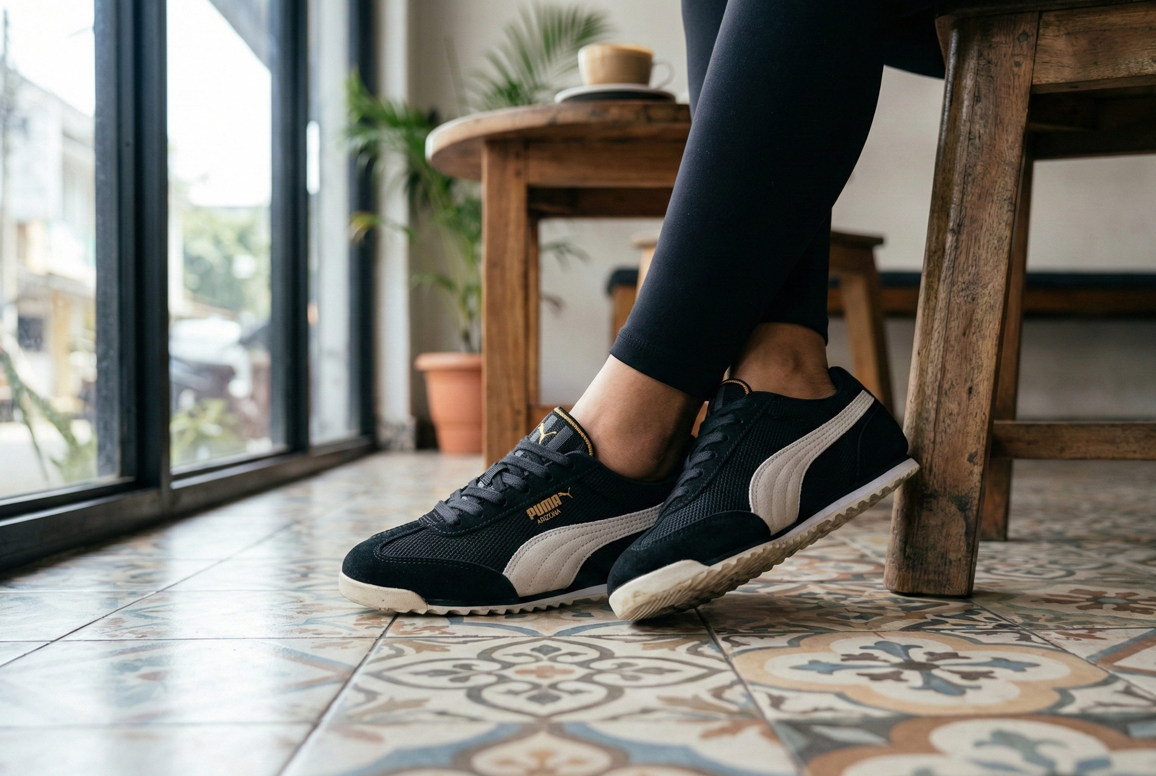 Person wearing black and white Arizona Sneakers Women on a patterned floor with a wooden chair and glass door in the background.