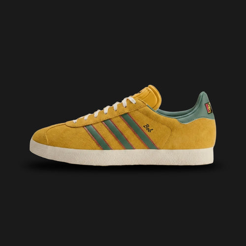 adidas Gazelle Jamaica x Bob Marley shoes in Bold Gold and Pure Ruby (Design Code: KJ3532). Featuring a premium suede upper in vibrant gold, iconic Rasta-colored serrated three-stripes, and Bob Marley’s image and signature on the tongue and lateral heel. Finished with a classic rubber outsole and gold-foil Gazelle branding. Luxuntique offers 100% authentic adidas x Bob Marley collaboration sneakers at the lowest price in Sri Lanka.
