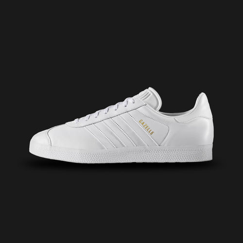 adidas Gazelle shoes in Cloud White and Gold Metallic (Design Code: BB5498). Featuring a premium full-grain leather upper in a tonal Triple White colorway with matching white three-stripes and tongue. Finished with a durable rubber cupsole and iconic Gold Metallic "GAZELLE" branding on the quarter panel. Luxuntique offers 100% authentic adidas leather heritage sneakers at the lowest price in Sri Lanka.