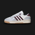 adidas Rivalry Low shoes in Light Solid Grey, Maroon, and Cloud White (Design Code: JH9600). Featuring a premium leather and synthetic upper in smooth Light Solid Grey with deep, contrasting Maroon three-stripes and heel branding. Designed with a retro 80s basketball silhouette and a durable rubber cupsole for daily street style. Luxuntique offers 100% authentic adidas heritage sneakers at the lowest price in Sri Lanka.