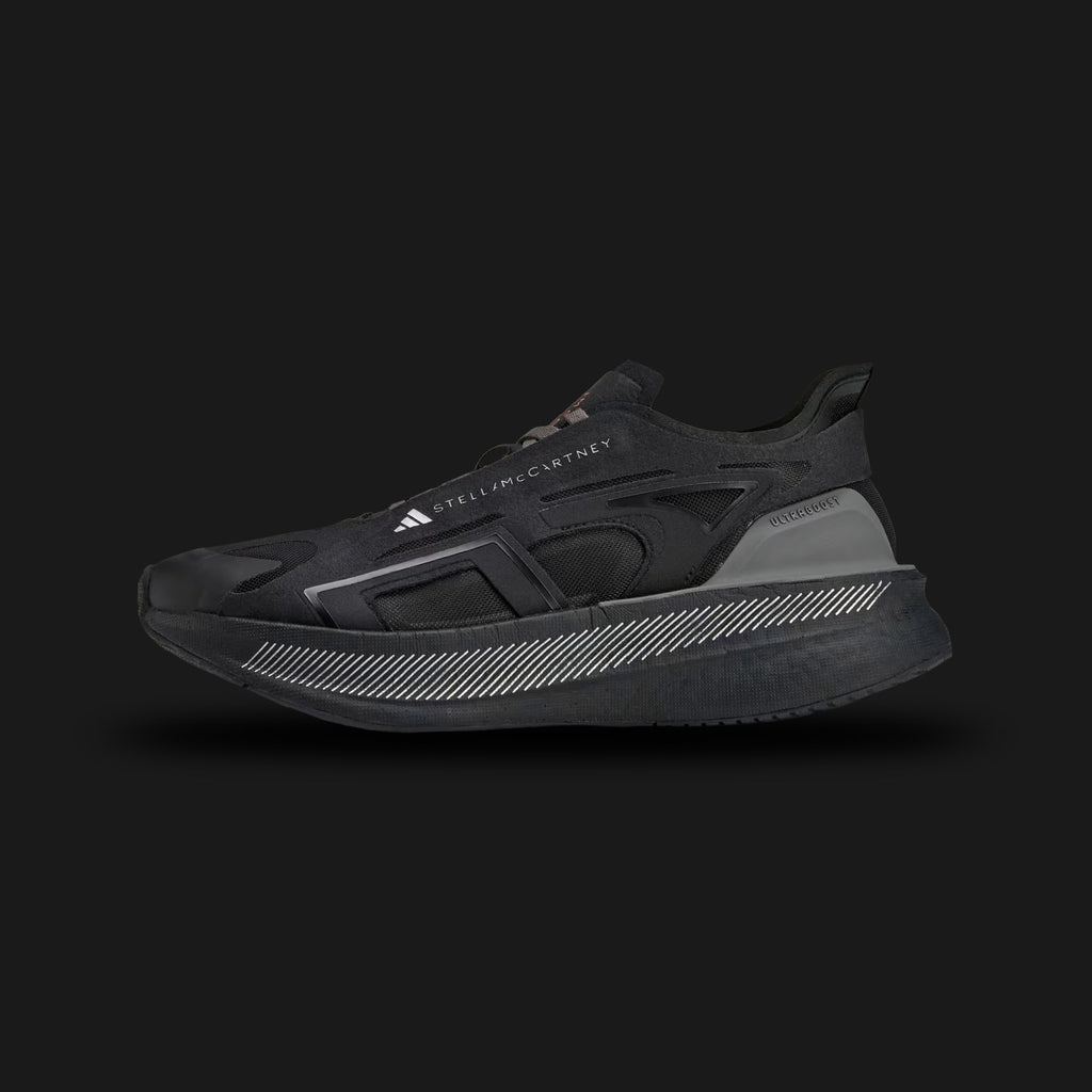 Adidas by Stella McCartney Ultraboost 5 shoes in Core Black, Crew Orange, and Charcoal (IE8771). Features a sustainable, breathable Core Black synthetic mesh upper encased in distinct Charcoal supportive overlays. Includes a thick, energy-returning Boost foam midsole, striking Crew Orange designer accents, and a durable rubber outsole. Luxuntique guarantees 100% authentic Adidas footwear in Sri Lanka.