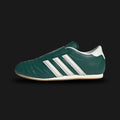 Adidas Taekwondo shoes in Collegiate Green, Off White, and Gum (JS4526). Features a premium soft leather slip-on upper in Off White with vibrant Collegiate Green Three Stripes and a thin, low-profile gum rubber outsole. Designed for a sleek, minimal martial-arts aesthetic. Luxuntique offers 100% authentic Adidas in Sri Lanka.