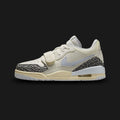Air Jordan Legacy 312 Low lifestyle sneakers in Sail, Cement Grey, Black, and Football Grey (Design Code: FQ7827-101). Featuring a premium layered leather upper combining a crisp Sail base with cool Football Grey accents and iconic Cement Grey detailing. Defined by a bold Black adjustable midfoot lockdown strap, classic Nike Swoosh, and signature hybrid Jordan design elements. Anchored by a vintage-inspired foam midsole housing a visible Air Max unit in the heel, all resting on a durable rubber outsole. Lux