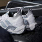 Adidas Rapidmove ADV 2 JI4196 - Lateral Midsole Close-up on Gym Floor showing Torsion System Embossed Panel, Lightstrike Pro Midsole Text, Grey Structural Overlays, Halo Silver Three Stripes & White Outsole Traction