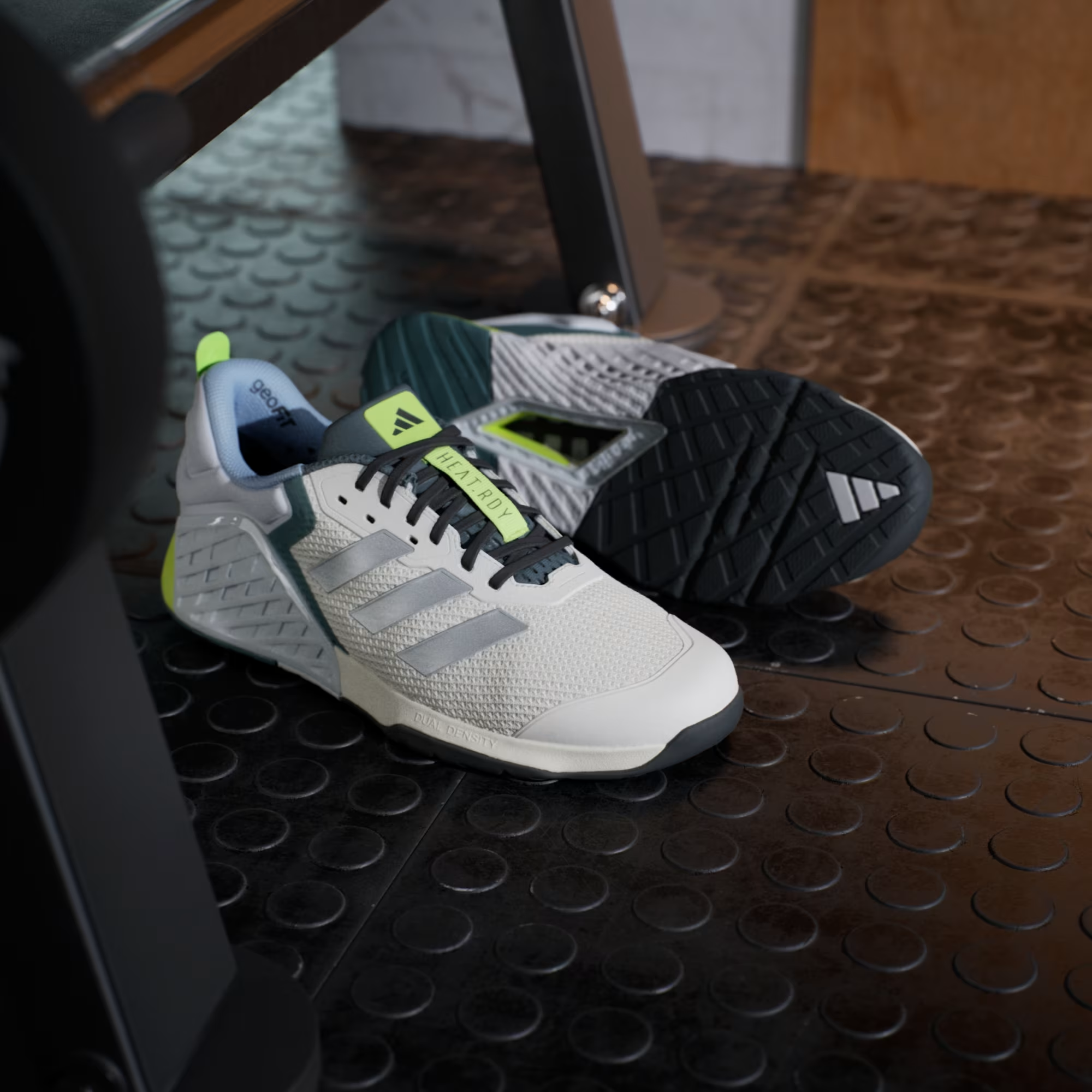 Adidas Dropset 3 JR1762 - Rear Heel Pair Shot on Wooden Gym Bench showing Chalk White Structured Heel Counter, Neon Yellow Pull Tab with Adidas Badge, Teal Collar Lining, geoFit Branding & Dual Density Midsole