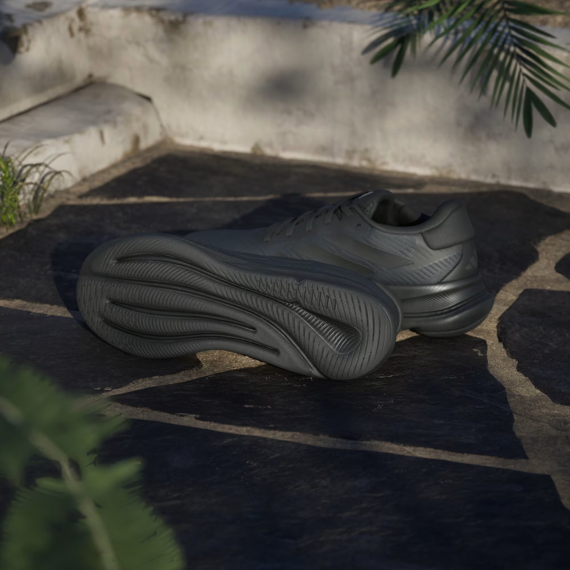 Adidas Supernova Ease IH2580 - Rear 3/4 Pair Shot on Cobblestone showing Structured Heel Counter, Carbon Midsole & Traction Pattern