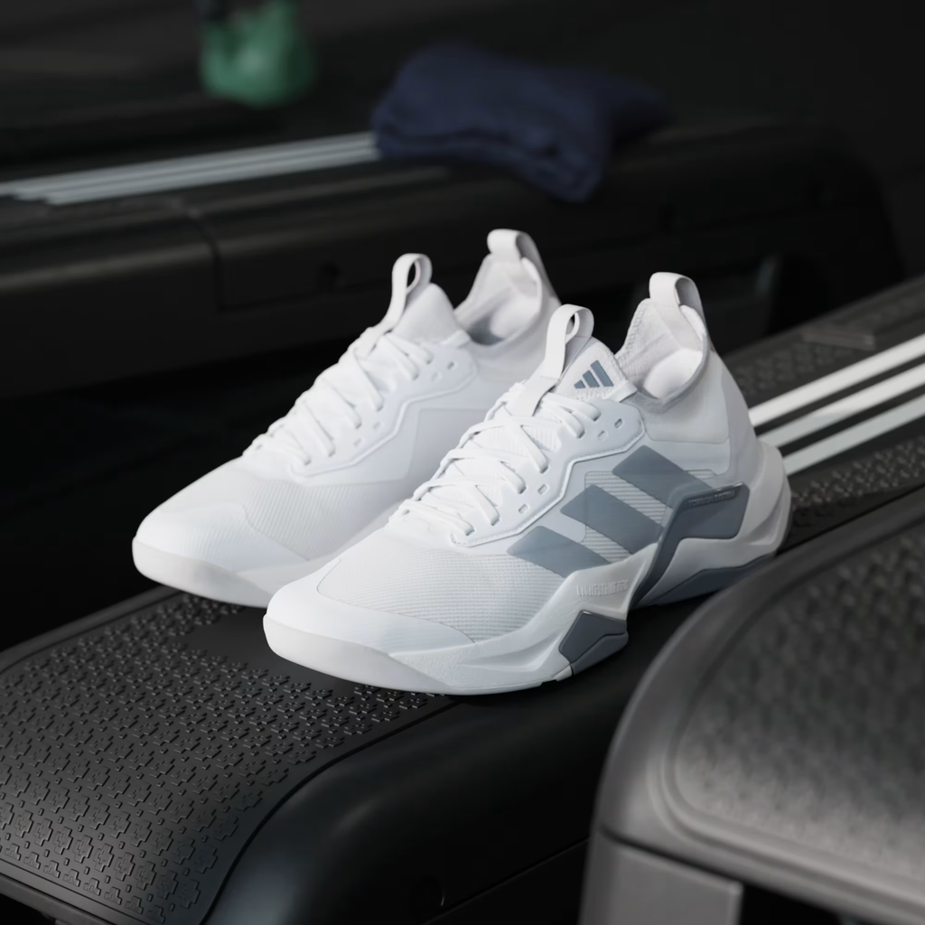 Adidas Rapidmove ADV 2 JI4196 - Clean Single Lateral Profile on Gym Floor with Kettlebells in Background showing Cloud White Mesh Upper, Grey Structural Overlays, Lightstrike Pro Midsole Text & Grey Rubber Outsole
