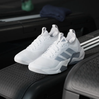 Adidas Rapidmove ADV 2 JI4196 - Clean Single Lateral Profile on Gym Floor with Kettlebells in Background showing Cloud White Mesh Upper, Grey Structural Overlays, Lightstrike Pro Midsole Text & Grey Rubber Outsole