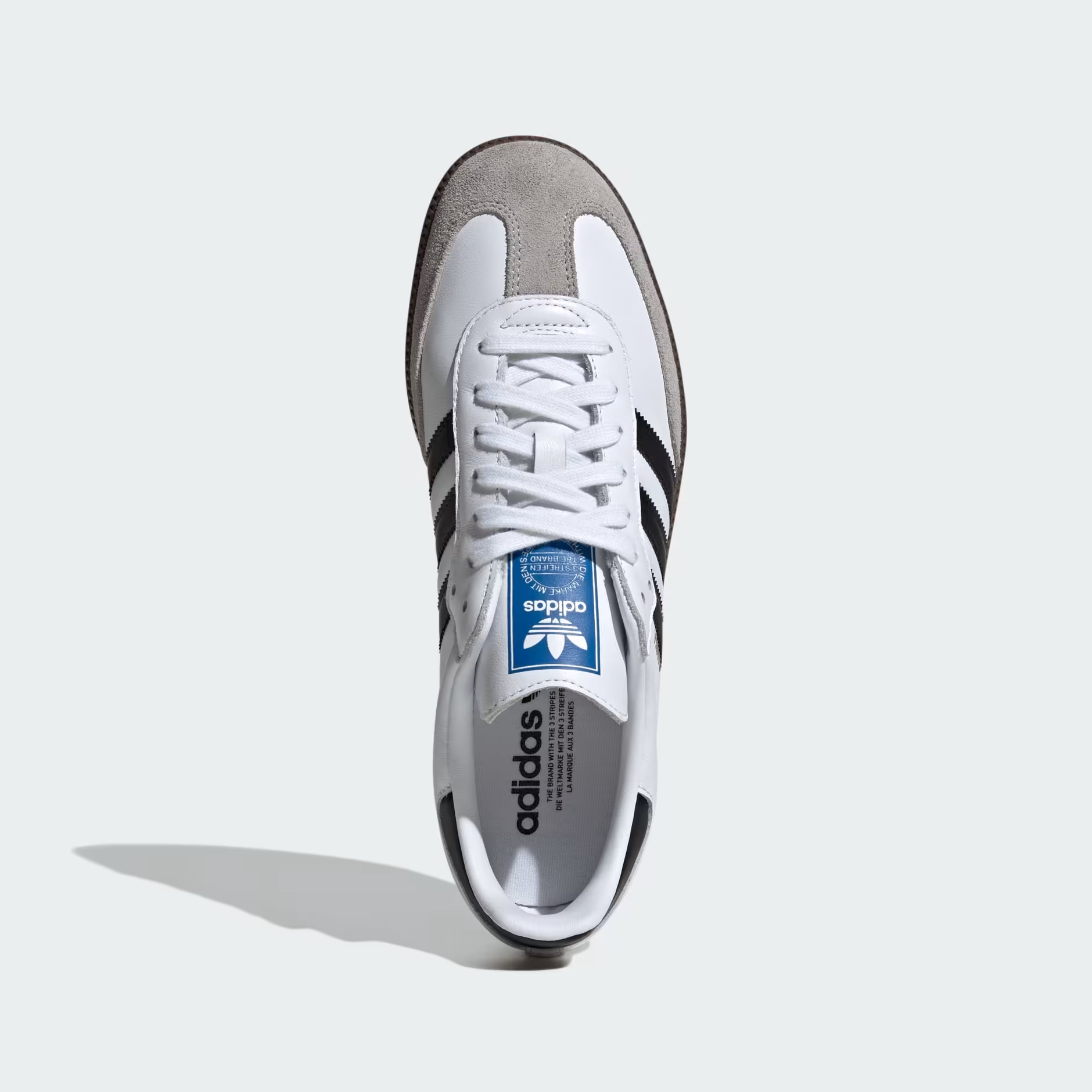 Adidas Samba OG B75806 - Rear 3/4 Pair Shot on Light Grey Background in Cloud White/Core Black/Clear Granite showing White Full-Grain Leather Upper, Gold Samba Wordmark on Lateral Quarter Panel, Core Black Three Stripes, Core Black Heel Counter, Blue Adidas Trefoil Tongue Badge & Gum Rubber Outsole