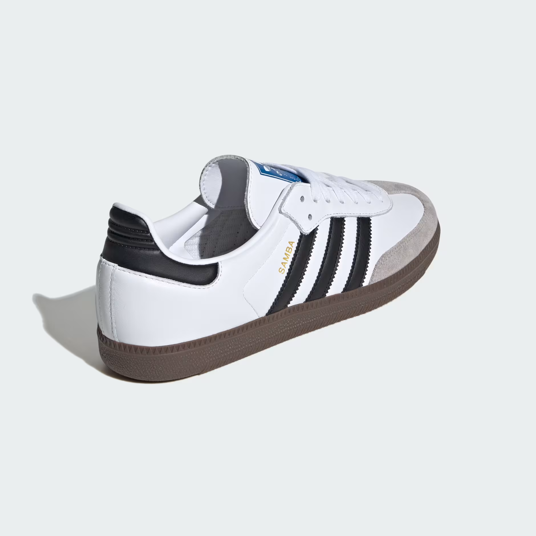 Adidas Samba OG B75806 - Lateral Midfoot Close-up showing Cloud White Full-Grain Leather Texture, Gold Samba Wordmark, Core Black Three Stripes Detail, Blue Adidas Trefoil Tongue Badge & Gum Rubber Outsole Edge