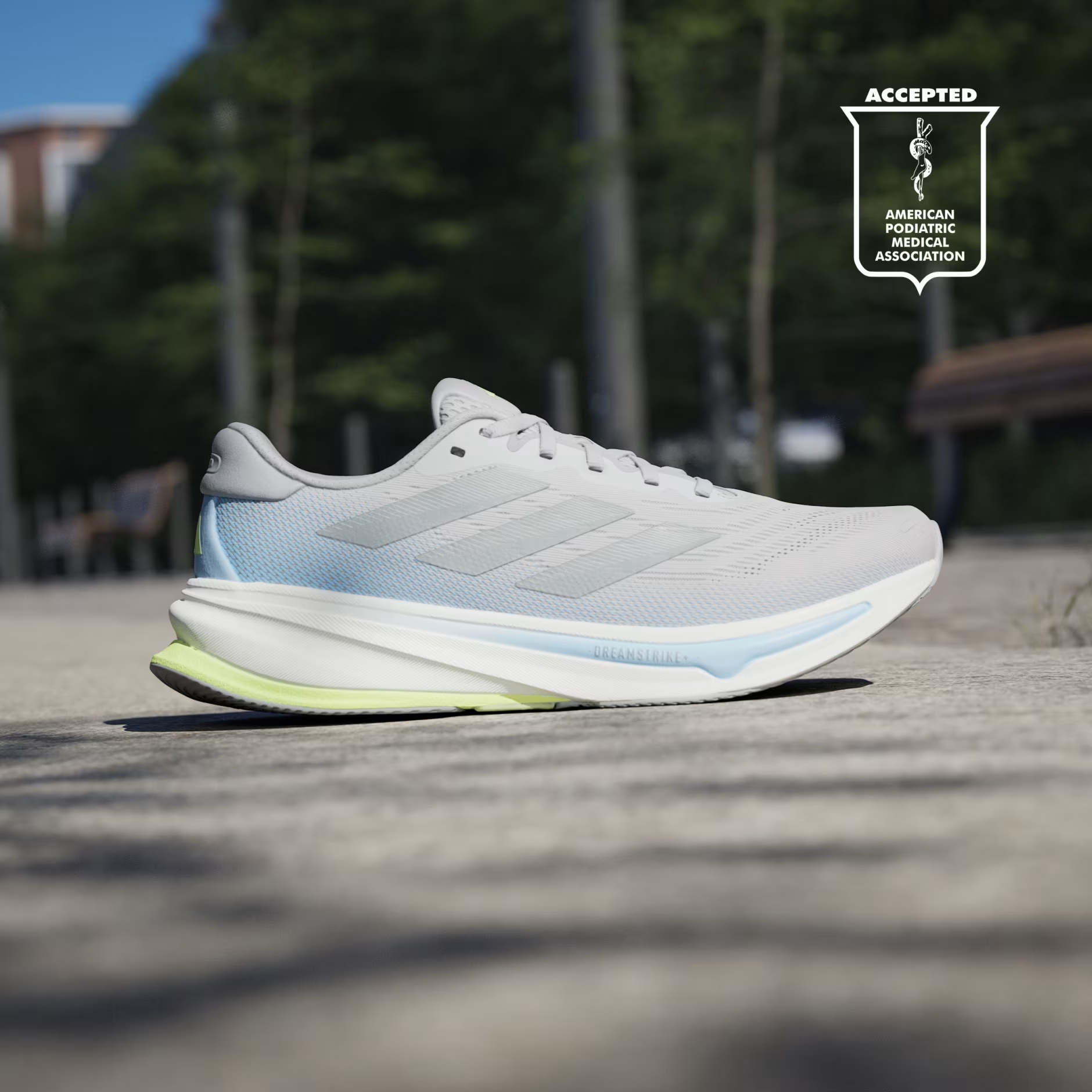 Adidas Supernova Rise 2 IH8708 - Front 3/4 Pair Shot on Cobblestone Street in Grey Two/Hi-Res Yellow showing Engineered Mesh Upper, Tonal Matte Silver Three Stripes, Light Blue Midsole Accent, White Dreamstrike+ Midsole & Hi-Res Yellow Bounce Outsole