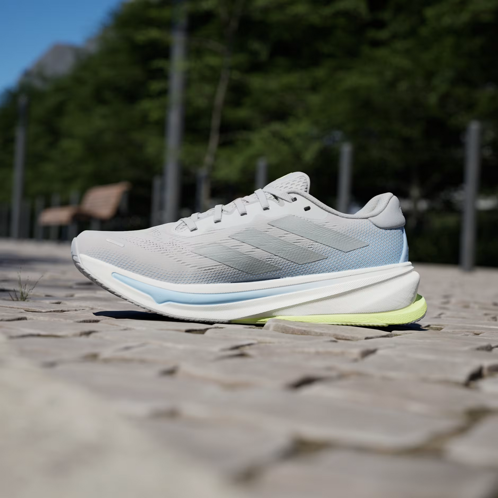Adidas Supernova Rise 2 IH8708 - Low Angle Lateral Pair Shot on Stone Ledge showing Grey Two Mesh Upper, Tonal Matte Silver Three Stripes, Dreamstrike+ Midsole Text, Light Blue Midsole Stripe & Hi-Res Yellow Bounce Outsole