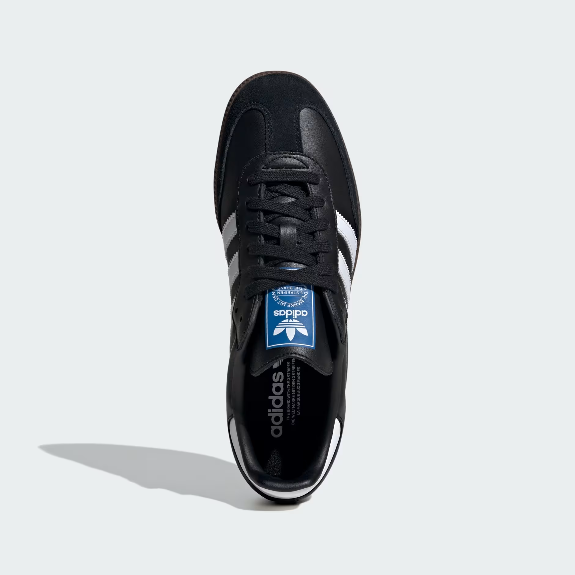 Adidas Samba OG B75807 - Rear 3/4 Single Shot on Light Grey Background in Core Black/Cloud White/Gum showing Core Black Full-Grain Leather Upper, Gold Samba Wordmark on Lateral Quarter Panel, Cloud White Three Stripes, Cloud White Heel Tab, Blue Adidas Trefoil Tongue Badge & Gum Rubber Outsole
