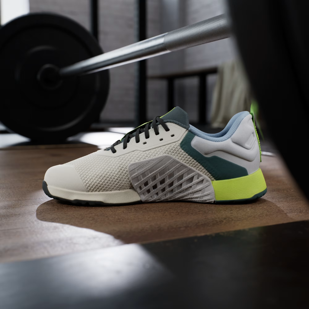 Adidas Dropset 3 JR1762 - Front 3/4 Pair Shot on Gym Floor in Chalk White/Silver Metallic showing HEAT.RDY Lace Dubrae, Silver Three Stripes, Teal Overlays, Neon Yellow Accents & geoFit Collar with Black Outsole Visible