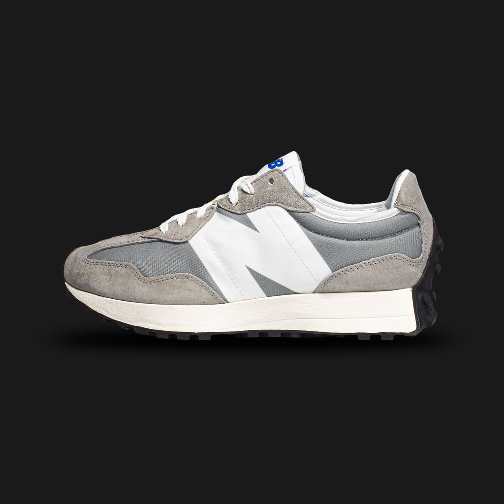 New Balance 327 sneakers in Team Away Grey with White (MS327LAB). Features a retro-inspired lifestyle silhouette that modernizes classic 1970s running shoes. Crafted with a premium split-suede and breathable nylon upper in a striking split Team Away Grey and light grey color-blocking, highlighted by an oversized, asymmetrical white leather 'N' logo. Includes a comfortable flared foam midsole and a distinctive black lugged rubber outsole that wraps around the heel for iconic heritage style and everyday lifes