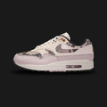 Nike Air Max 1 '87 premium lifestyle sneakers in Light Orewood Brown, Malt, Velvet Brown, and Multi-Colour (Design Code: HF5338-100). Featuring a richly textured upper that blends breathable Light Orewood Brown mesh with premium Malt suede overlays. Anchored by a bold, dark Velvet Brown suede mudguard and accented with Multi-Colour detailing. Supported by a classic white foam midsole housing the iconic, visible Air Max heel unit. Luxuntique offers 100% authentic Nike retro footwear at the lowest price in Sr