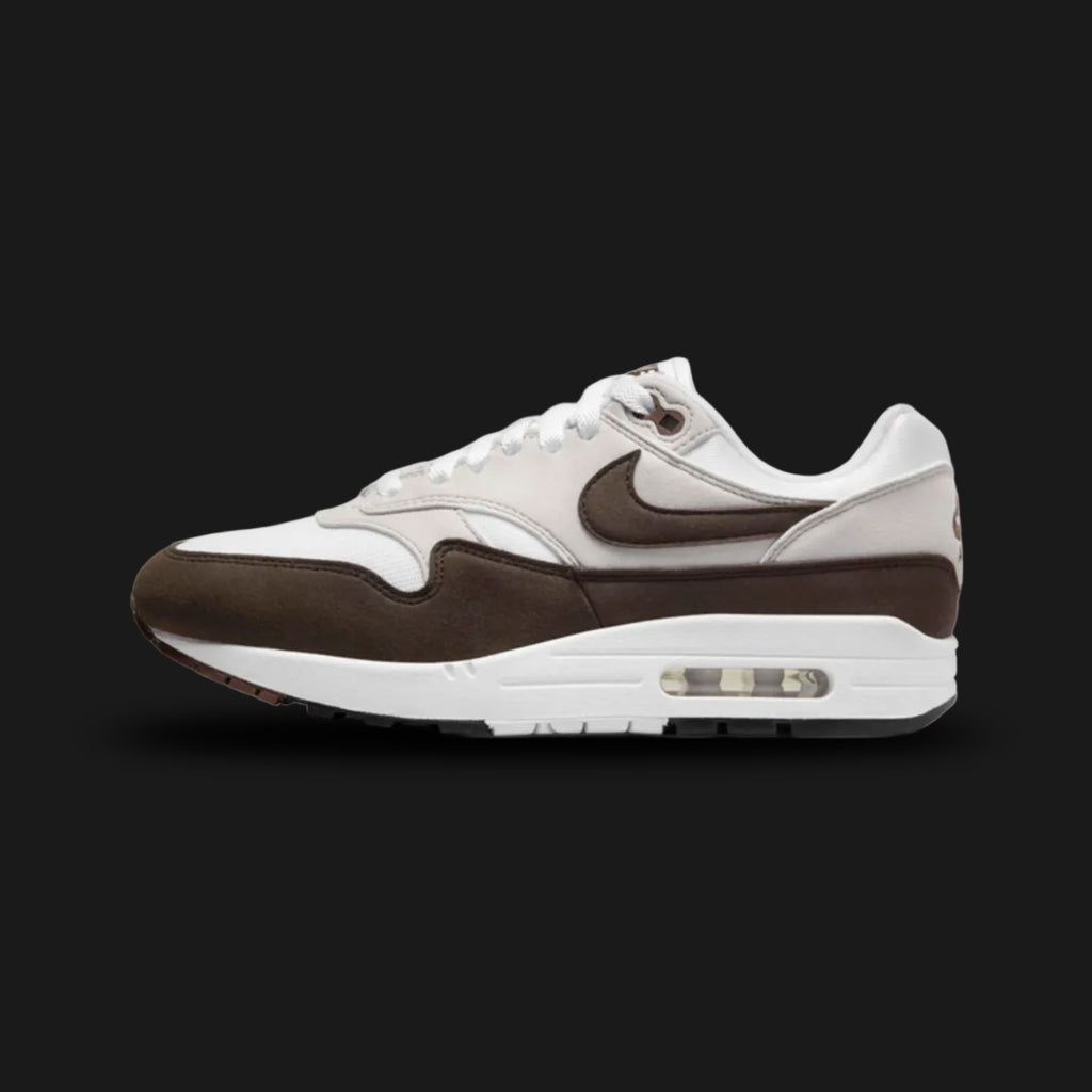 Nike Air Max 1 sneakers in Baroque Brown, Neutral Grey, White, and Black (DZ2628-004). Featuring a rich Baroque Brown suede mudguard and Swoosh over a Neutral Grey and White mesh upper. Anchored by a crisp White midsole with visible Air cushioning and a tri-color outsole. Luxuntique offers 100% authentic Nike footwear in Sri Lanka.