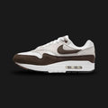 Nike Air Max 1 sneakers in Baroque Brown, Neutral Grey, White, and Black (DZ2628-004). Featuring a rich Baroque Brown suede mudguard and Swoosh over a Neutral Grey and White mesh upper. Anchored by a crisp White midsole with visible Air cushioning and a tri-color outsole. Luxuntique offers 100% authentic Nike footwear in Sri Lanka.
