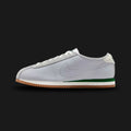 Nike Cortez Leather in Wolf Grey, Sport Green, and Gum (HQ1841-001). Features a premium Wolf Grey leather upper with vibrant Sport Green accents on the Swoosh and heel tab. Signature Summit White wedge midsole and a serrated Gum Medium Brown outsole. Luxuntique offers 100% authentic Nike footwear in Sri Lanka.