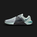Nike Metcon 10 training shoes in Light Pumice, Black, and Mineral Slate (HJ1875-007). Features an enlarged Hyperlift plate in the heel for stability during heavy lifts and an extended rubber rope wrap for midfoot durability. Breathable mesh upper with a dual-density midsole for versatile cushioning. Luxuntique offers 100% authentic Nike in Sri Lanka.