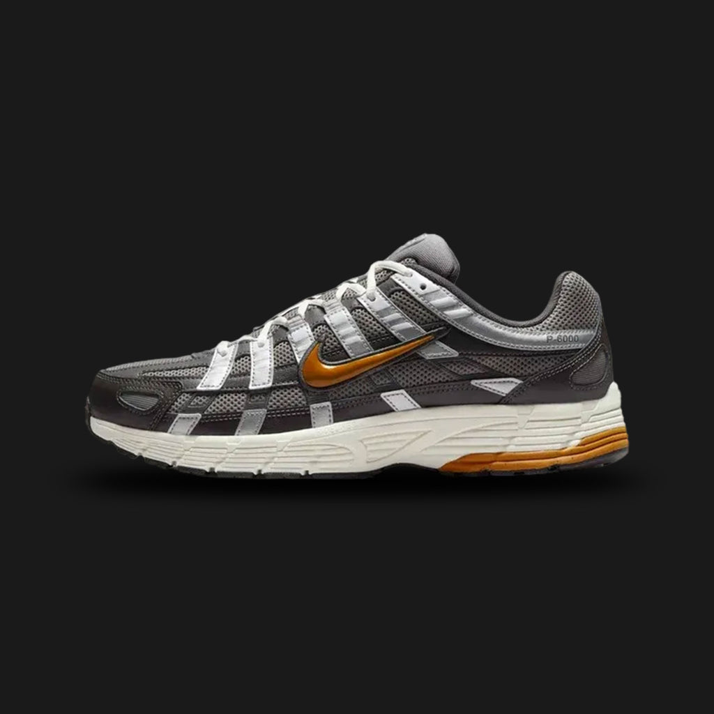 Nike P-6000 retro running shoes in Medium Ash, Flat Pewter, White, and Desert Ochre (Design Code: CD6404-204). Featuring a breathable Medium Ash mesh upper heavily layered with Flat Pewter synthetic leather overlays for a distinct Y2K cage aesthetic. Accented with warm Desert Ochre detailing on the Swoosh and outsole, built on a comfortable Cushlon midsole. Luxuntique offers 100% authentic Nike Y2K lifestyle sneakers at the lowest price in Sri Lanka.