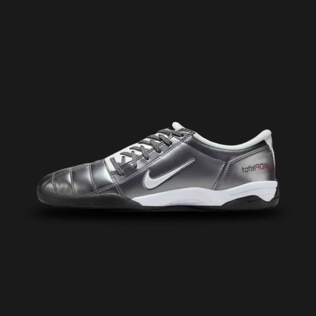 Nike Total 90 lifestyle and street shoes in Light Graphite, White, Black, and Metallic Summit White (Design Code: HQ2851-001). Featuring a sleek Light Graphite synthetic upper defined by the iconic asymmetrical off-center lacing system and signature 3D textured striking zones. Accented with sharp Black details, a crisp White Swoosh, and subtle Metallic Summit White highlights, all built on a durable rubber outsole for street-ready traction. Luxuntique offers 100% authentic Nike retro footwear at the lowest 