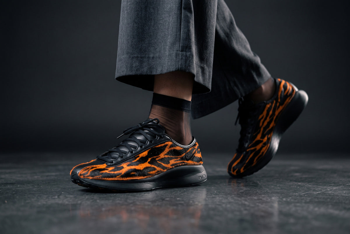 Close-up of original Nike Air Superfly LX in orange and black tiger-stripe pony hair, worn with charcoal trousers, available at Luxuntique Sri Lanka