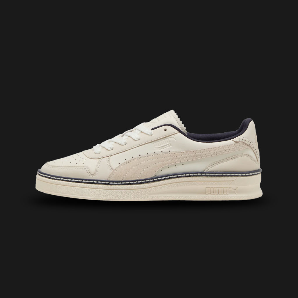 Puma Indoor Regal Grace unisex sneakers in Warm White and Frosted Ivory (402583_01). Features a sophisticated, low-profile silhouette inspired by vintage indoor court styles. Crafted with premium synthetic and textile materials, including a clean Warm White upper with subtle Frosted Ivory overlays. Includes a non-marking, flat rubber outsole for indoor performance and a sleek, versatile design suitable for daily street style. Luxuntique guarantees 100% authentic Puma footwear in Sri Lanka.