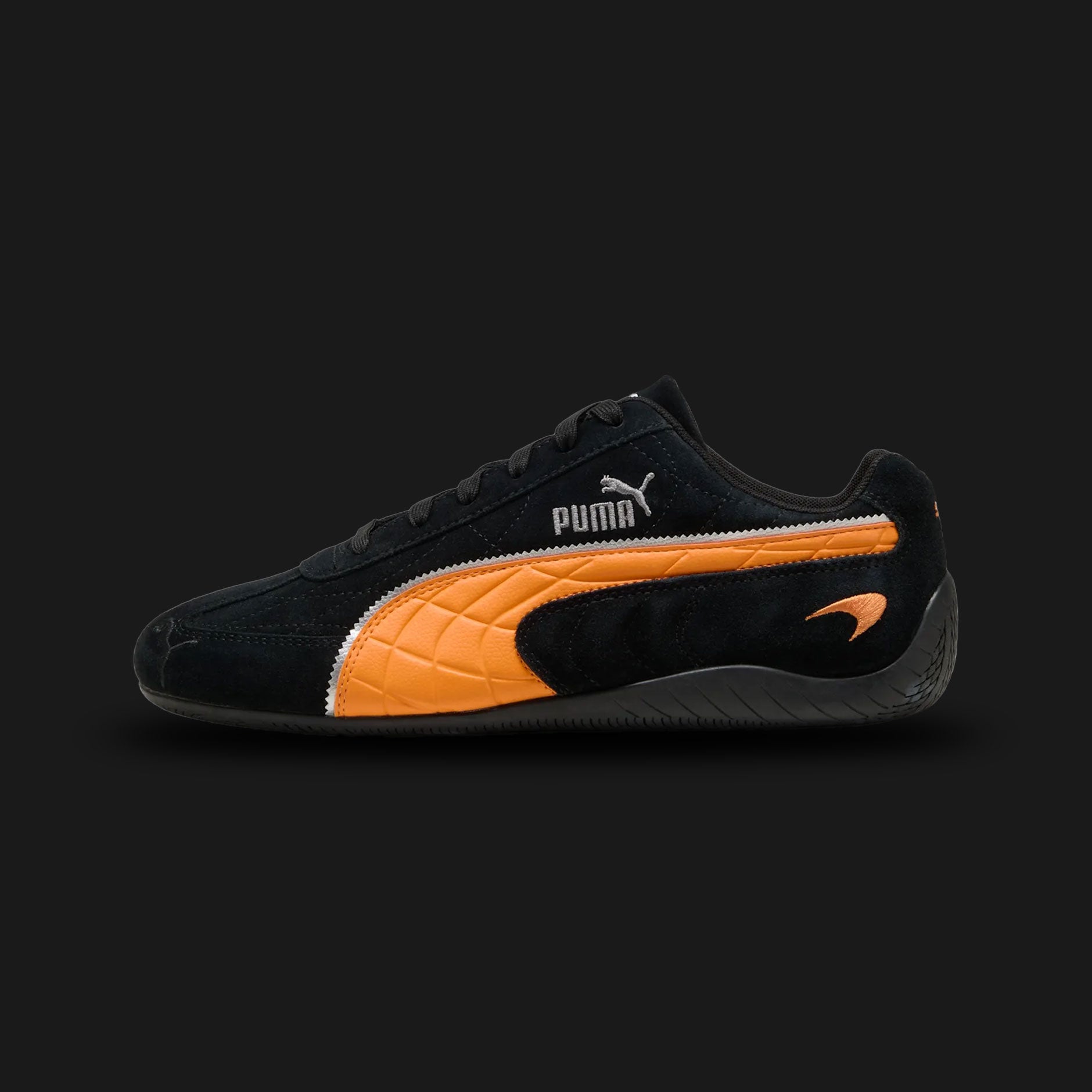 PUMA McLaren Racing Speedcat Unisex sneakers in PUMA Black and Bright Papaya (309452_01). Features a premium black leather upper with vibrant McLaren orange accents and the official McLaren Racing logo on the tongue. Low-profile tire-tread rubber outsole and rounded driver's heel. Luxuntique offers 100% authentic PUMA in Sri Lanka.