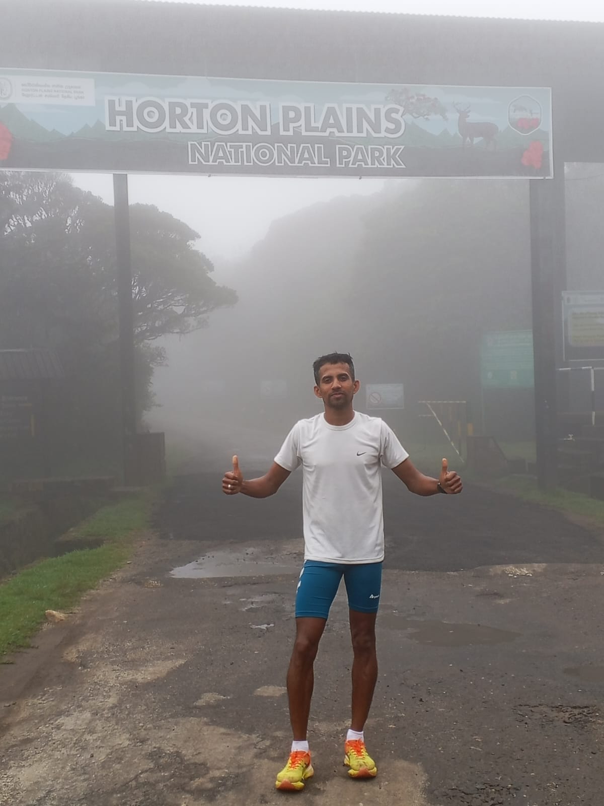 Udara Chanaka Rupasinghe giving a thumbs-up in the mist at the entrance to Horton Plains National Park